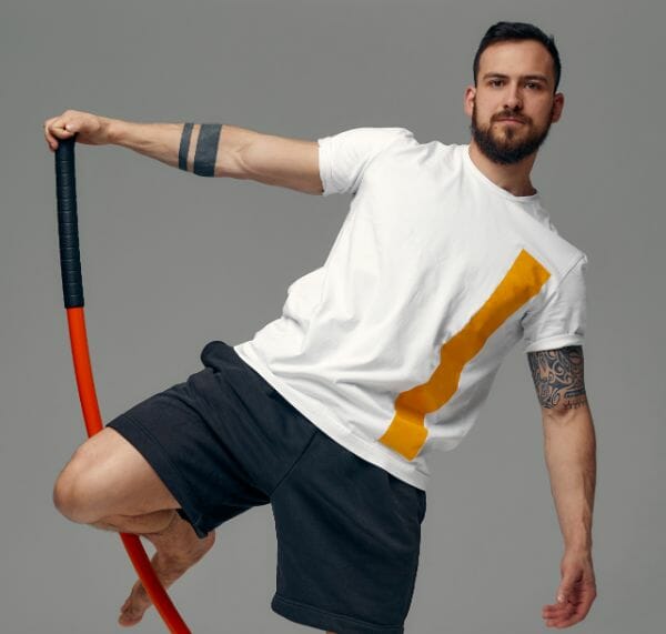 fighter white tshirt black shorts stands fighting artificially pose holds fight stick studio background (1)