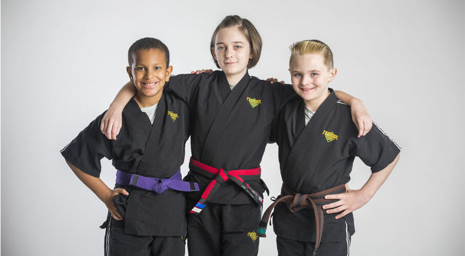 Three children stand proud in their Premier Martial Arts uniforms. 