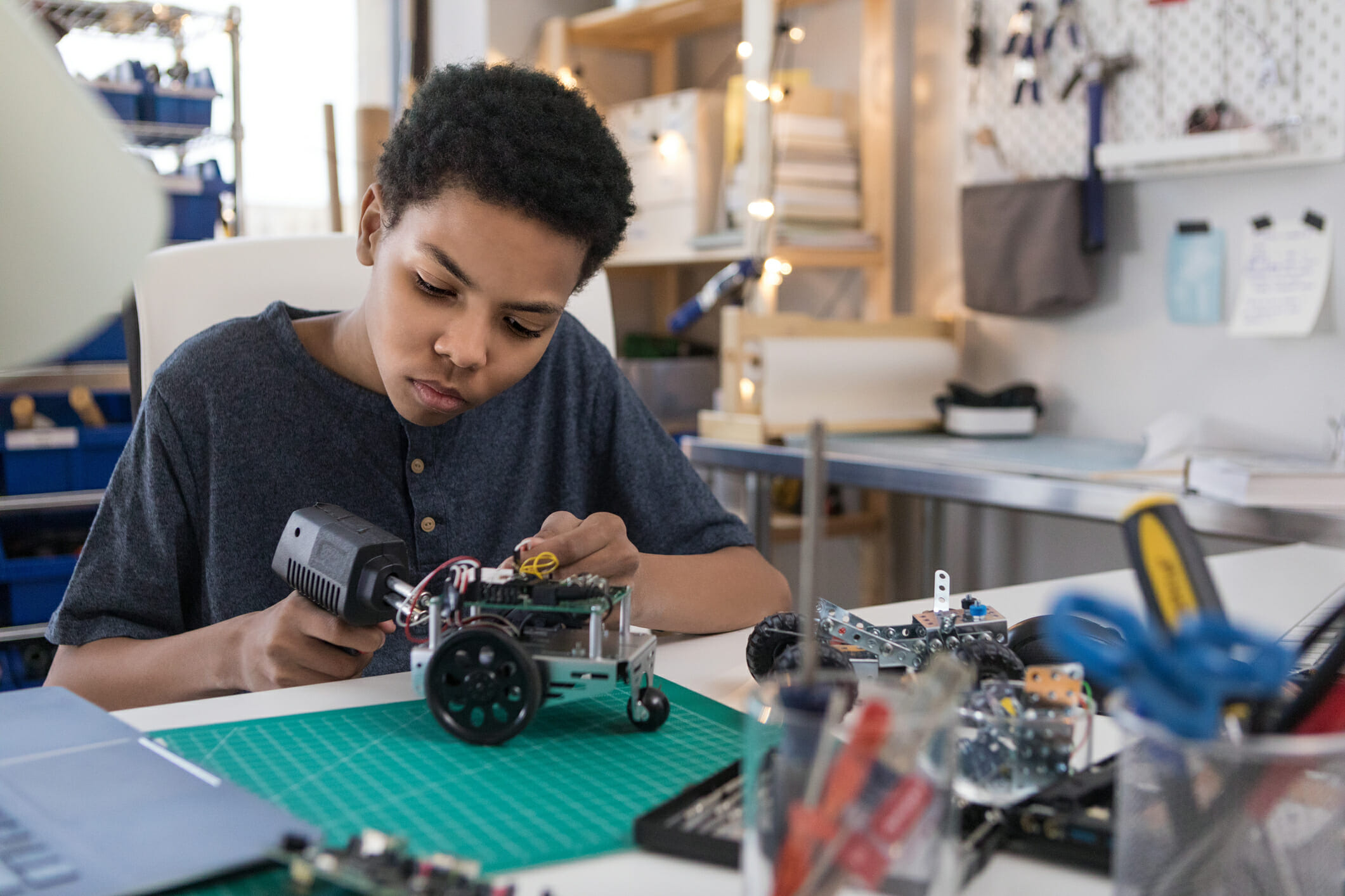 Teen boy solders wires to build robot
