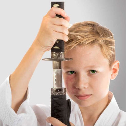 A boy with a samurai sword in martial arts training